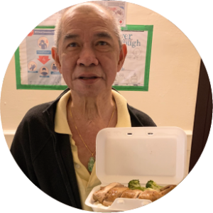 Older bald chinese man standing looking at the camera holding some food